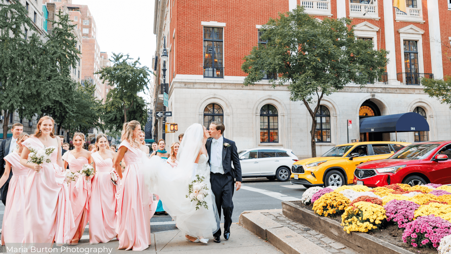 Bride and Groom kissing while crossing the street with wedding party