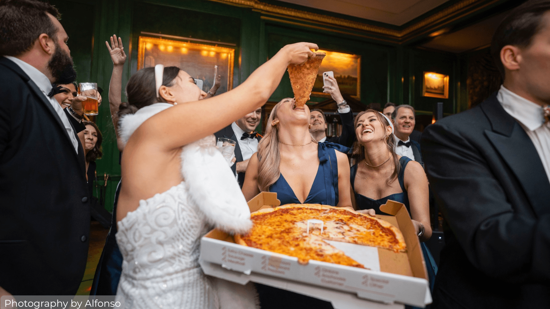 Bride feeding a bridesmaid pizza on the dance floor